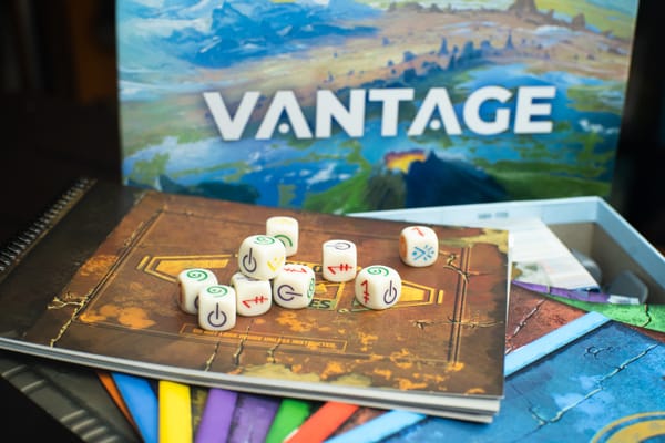 Dice from the game Vantage on top of a series of story books used in the game.
